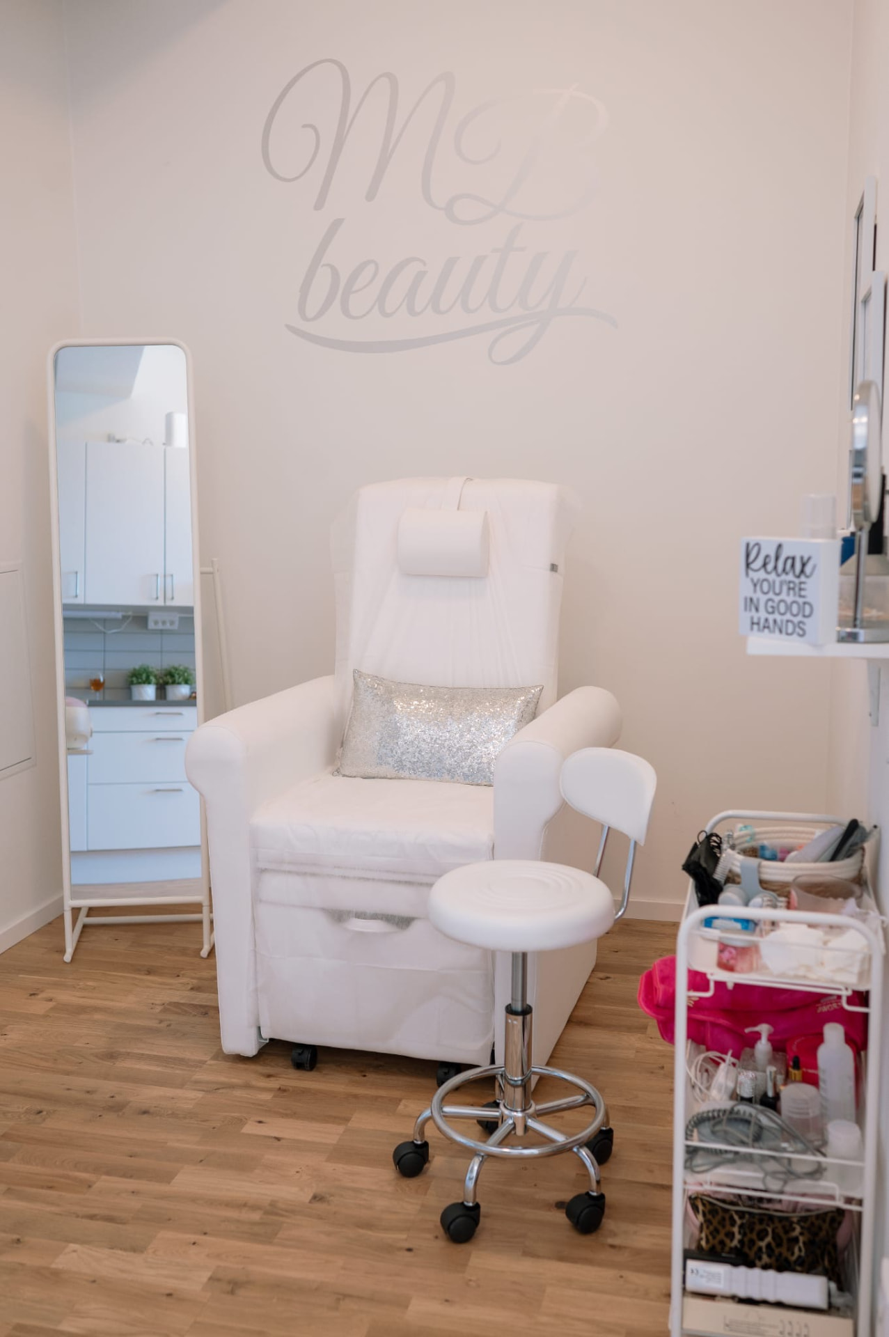 Fotvårdsplatsen hos MB Beauty Love med vit stol och MB beauty-logotyp på väggen