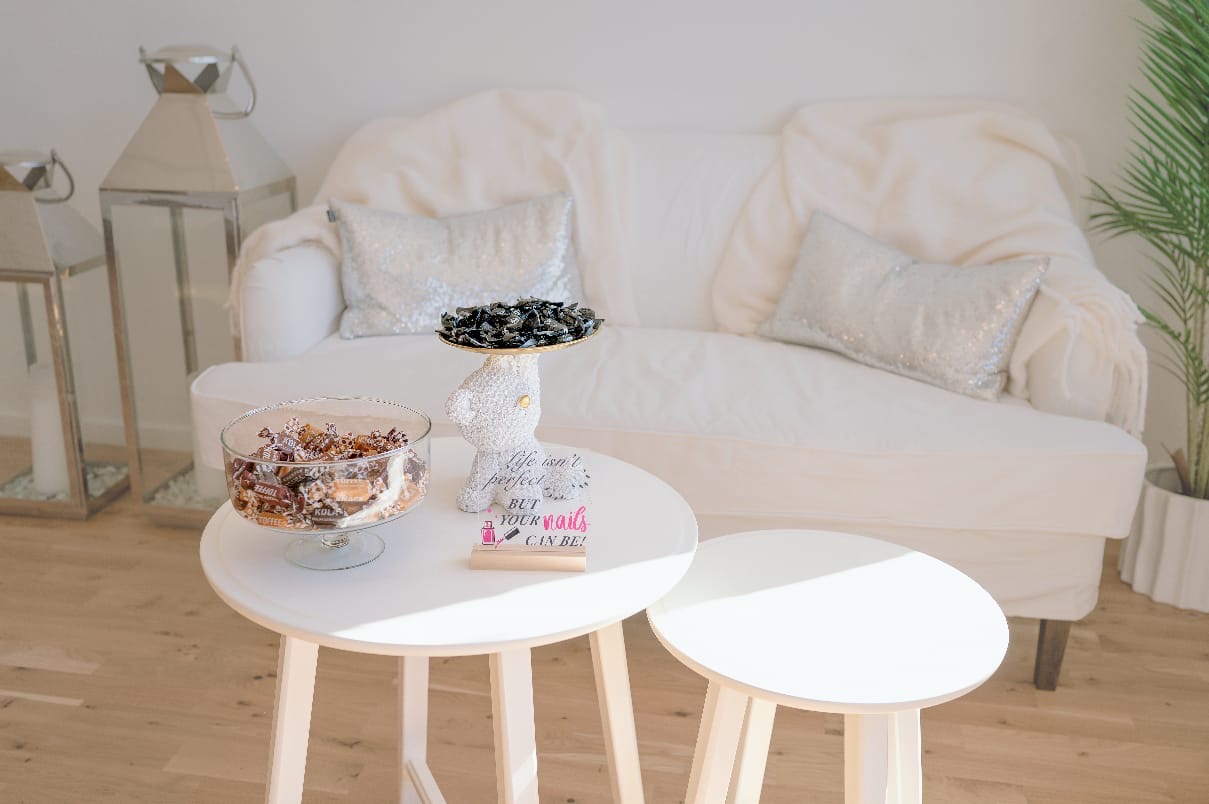 Väntrummet med vit soffa och små runda bord hos MB Beauty Love